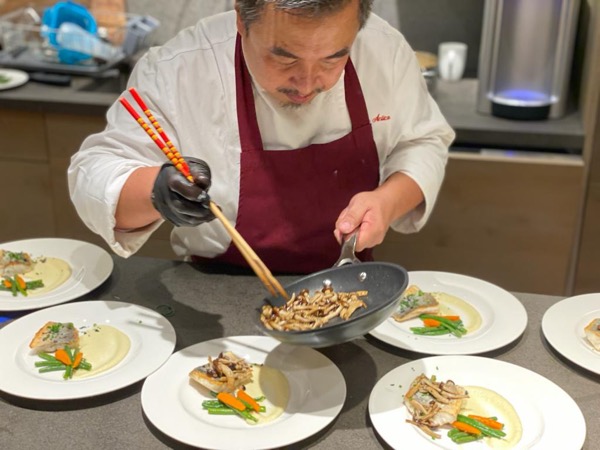 Chef Hiro preparing food on white plates using chop sticks